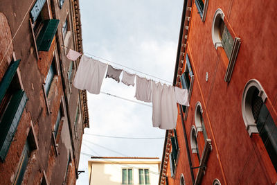 Low angle view of laundry drying amidst buildings against sky