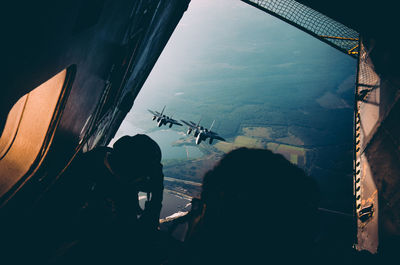 Rear view of man looking through airplane window