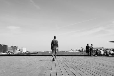 Rear view full length of man on walkway against river in city