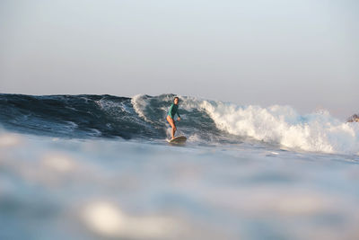 Man surfing in sea against sky