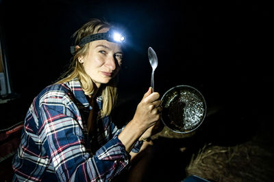 Woman with head light smiling after having dinner in a camp