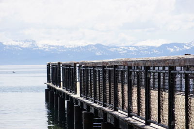 Wooden posts on pier over sea against sky