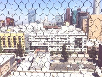 Chainlink fence against sky in city