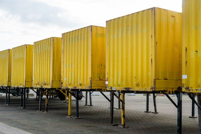 Yellow metallic structure on pier by building against sky