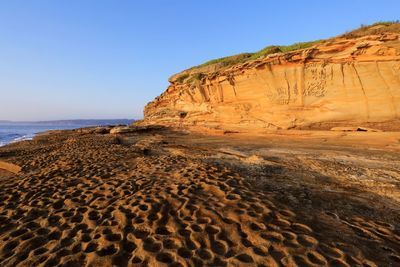 Rock formations on beach against clear sky