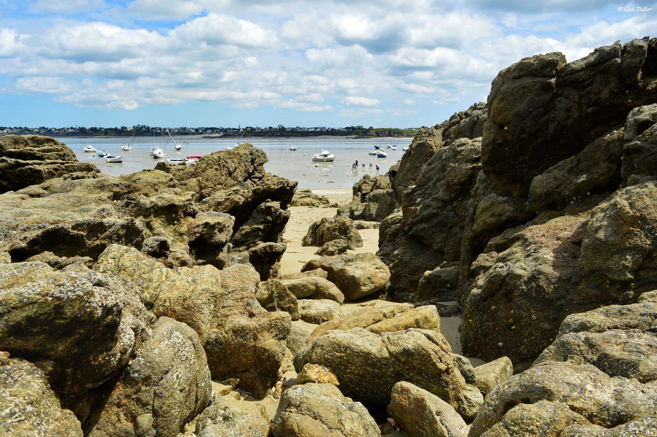 ROCKS BY SEA AGAINST SKY