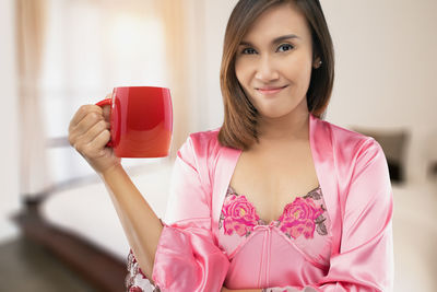 Portrait of a smiling young woman holding pink flower