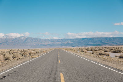 Road by desert against sky