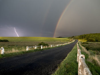 Scenic view of field against rainbow in sky