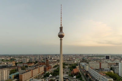 Communications tower and buildings in city against sky