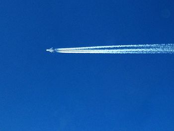 Low angle view of vapor trail against blue sky