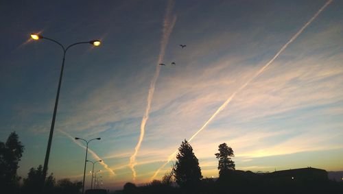 Low angle view of silhouette street lights against sky during sunset