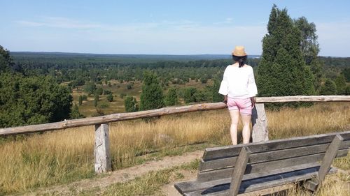 Rear view of woman standing by railing against sky