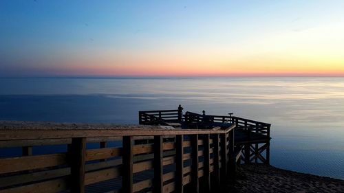 Pier over sea against sky during sunset