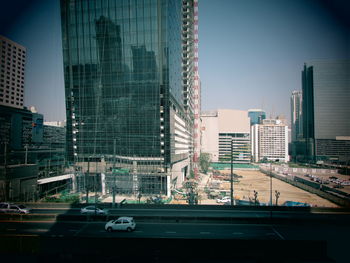 Road in front of modern glass buildings during sunny day