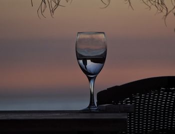 Close-up of wineglass against sky at sunset