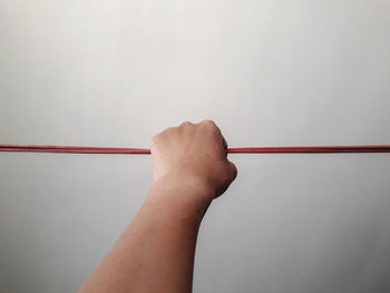 Cropped hand of person holding cables against gray background