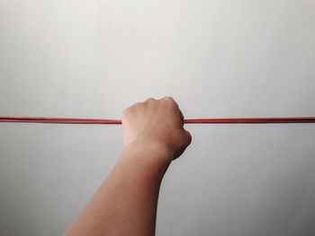 Close-up of hand holding red light against wall