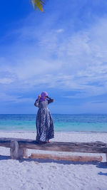 Person in hat on beach against sky