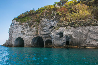 Rock formation by sea against blue sky