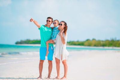 Friends standing at beach against sky