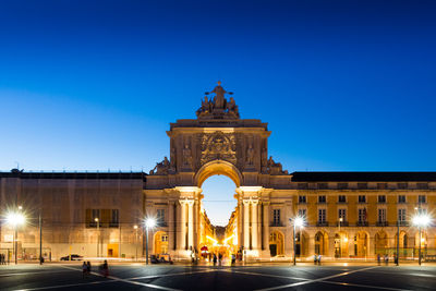 View of illuminated building against blue sky at night