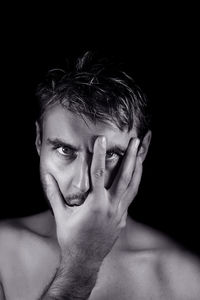 Close-up portrait of angry man with hand on face against black background