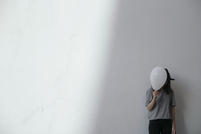 Woman holding balloon by white wall