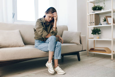 Young woman sitting on sofa at home