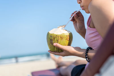 Close up of woman drinking fresh coconut juice at beach person