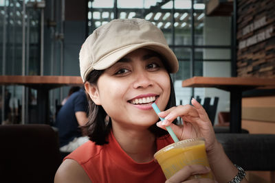 Close-up portrait of smiling woman holding drink at restaurant