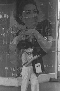 Portrait of woman photographing reflection on glass