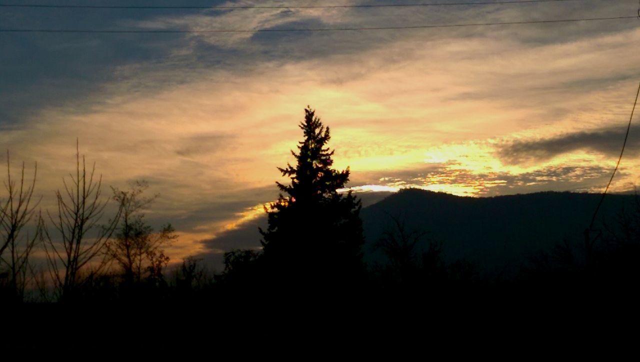 SILHOUETTE OF MOUNTAIN AGAINST CLOUDY SKY AT SUNSET