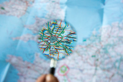Cropped hand holding magnifying glass over map