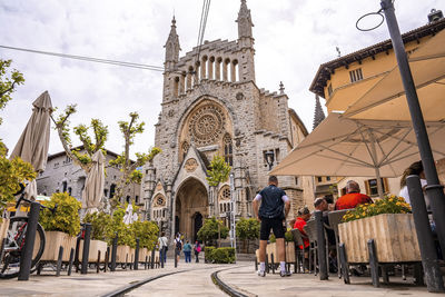 Church of sant bartomeu de soller by restaurant against cloudy sky in old town