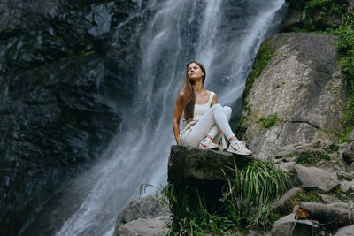 Rear view of woman standing against waterfall