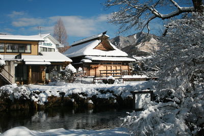 Houses by lake against buildings during winter