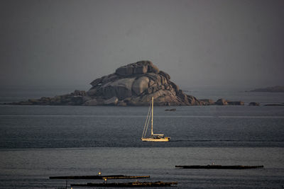 Sailboat on rock by sea against sky