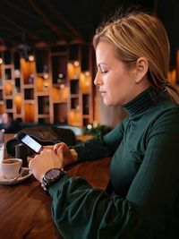 Mid adult woman using mobile phone at table