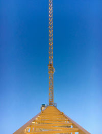 Low angle view of crane against clear blue sky