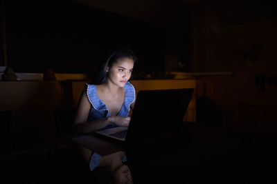 Young woman using laptop in darkroom