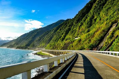 Scenic view of road by mountains against sky