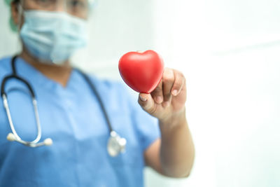 Midsection of doctor holding heart shape against white background
