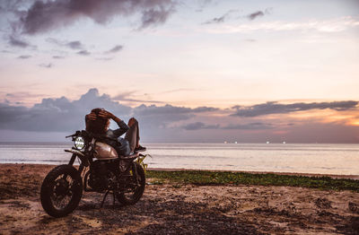 Bicycles on beach against sky during sunset