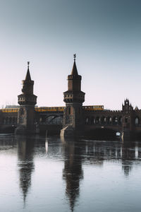 Bridge over river in city against clear sky