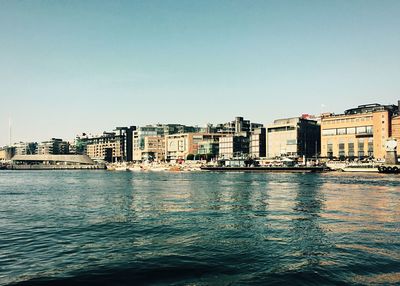 Sea by buildings against clear sky