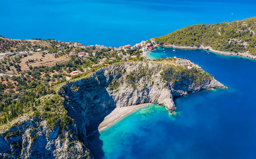 High angle view of rocks by sea against blue sky