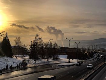 Cars on road against sky during sunset