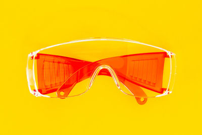 Close-up of sunglasses against orange background