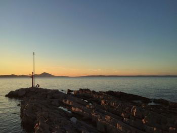 Rocky shore against sky during sunset